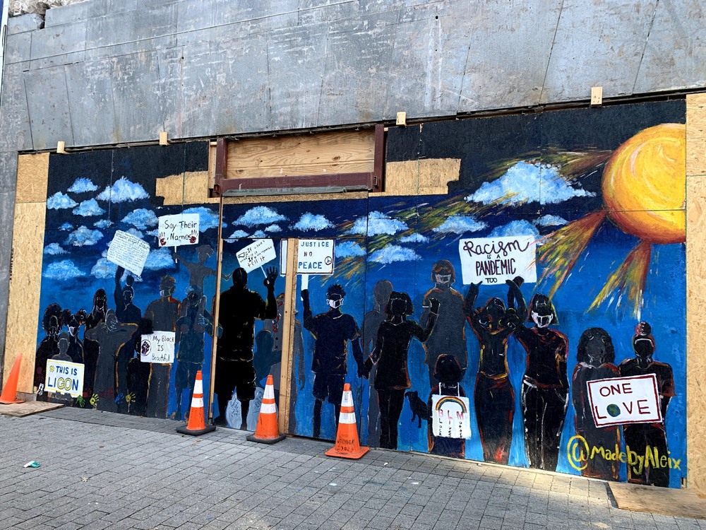 Mural depicting protestors holding signs calling attention to racism