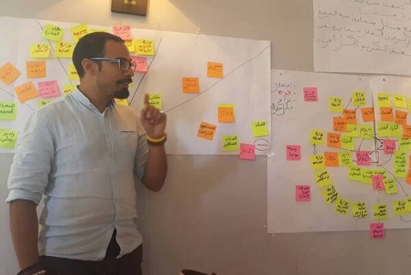 Trainer stands in front of charts with post-it notes