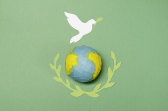 Green background with paper globe and dove cutouts representing peace