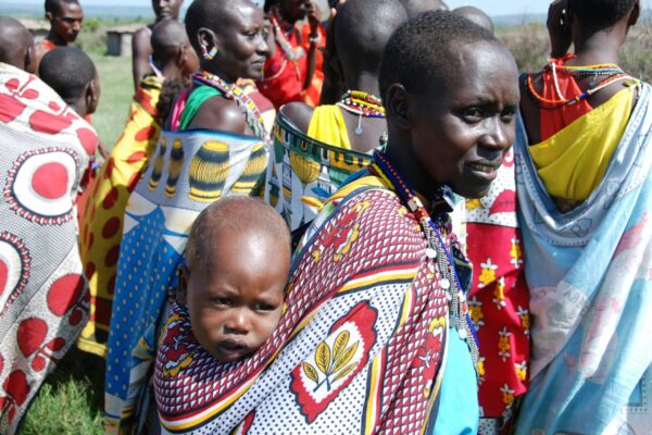 A Kenyan woman dressed in traditional clothing carrying her child