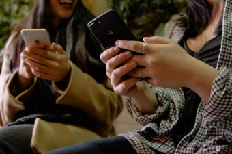 Cropped image of two women chatting while holding their mobile phones