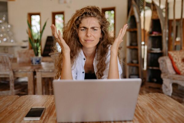 Woman looking at a computer throwing her hands up in frustration